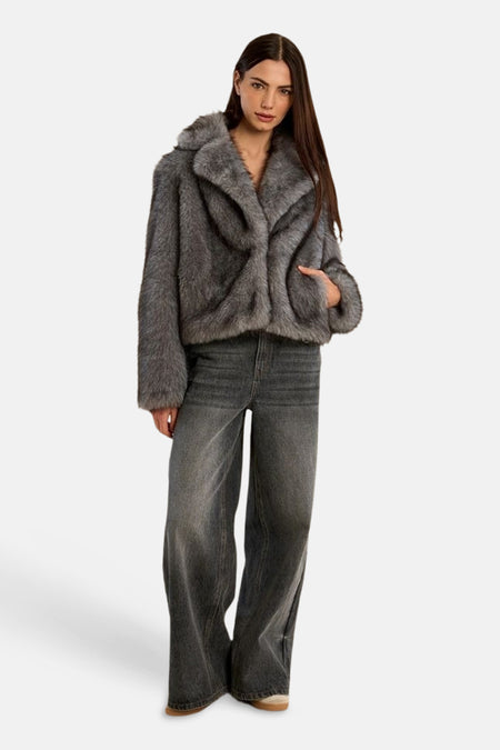 Femme portant une veste courte grise à col en fausse fourrure avec un jean gris