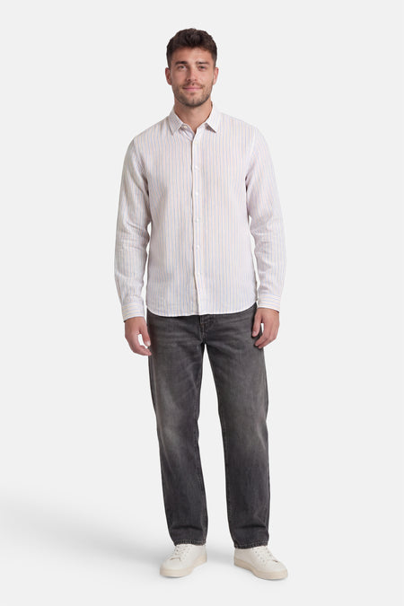 Chemise à rayures multicolores de Le Temps des Cerises portée par un homme avec un jean foncé et des baskets blanches.