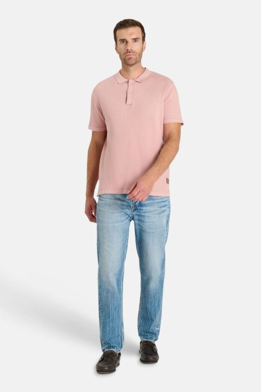 Roze polo van Le Temps des Cerises, met geribbelde textuur en discrete knopen, gedragen met een casual spijkerbroek.