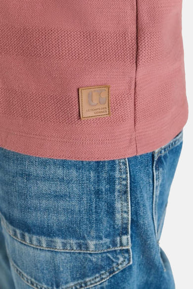 Polo brique à manches courtes de Le Temps des Cerises, avec un écusson de la marque, porté avec un jean.
