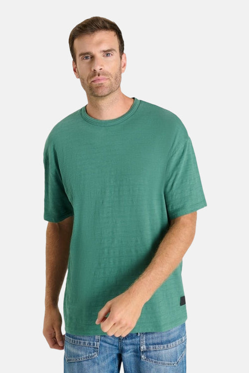T-shirt à manches courtes vert de Le Temps des Cerises, sur un homme portant un jean bleu.