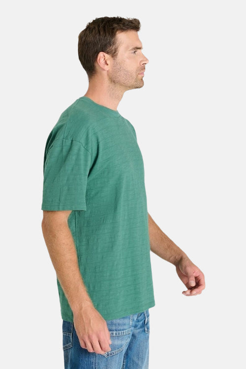 T-shirt à manches courtes vert de Le Temps des Cerises, avec des détails de texture subtils, porté avec un jean.