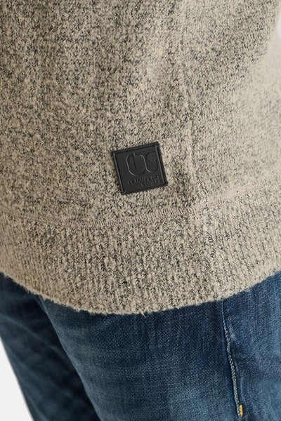Beige ronde hals trui van Le Temps des Cerises, gevlekt gebreide textuur, logo patch onderaan, gedragen met een spijkerbroek.