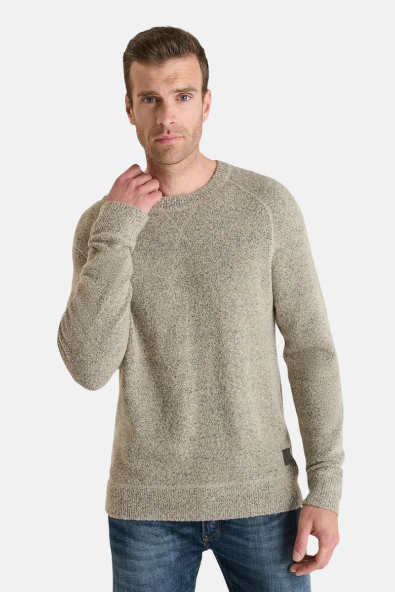 Beige ronde hals trui van Le Temps des Cerises gedragen met een spijkerbroek, de man legt een hand op zijn nek.