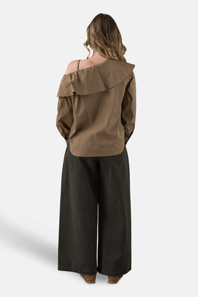 Beige blouse met lange mouwen van ADORE, met ruchedetail op de schouder, gedragen met een donkergroene wijde broek.
