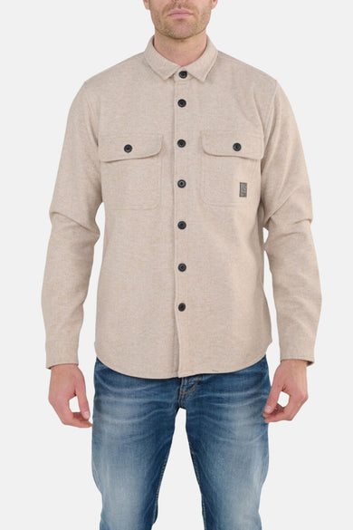 Beige overhemd met lange mouwen van Le Temps des Cerises, met knoopbare borstzakken en gedragen blauwe jeans.