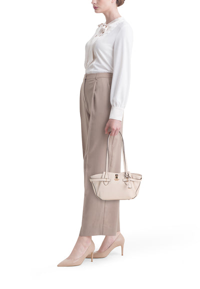 Ecru leather shoulder bag with gold-tone hardware and top handles, worn by model in side view with white blouse and beige trousers