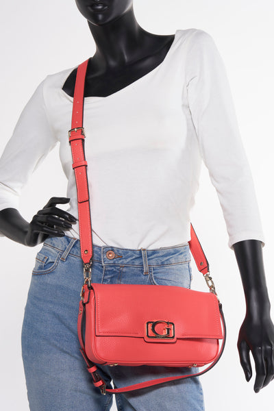 Roze schoudertas van Guess, gedragen als schoudertas door een model met een spijkerbroek en een wit T-shirt.
