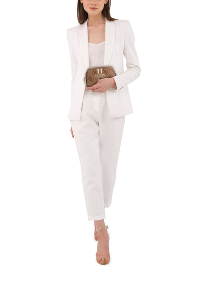 Sac à bandoulière brun de Guess, porté avec un tailleur pantalon blanc et des sandales à talons transparents.
