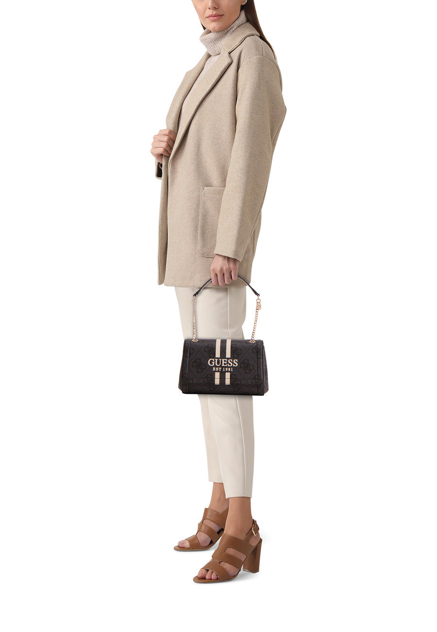 Zwarte Guess schoudertas met monogrampatroon en witte strepen, gedragen met een beige jas en bruine hakken.