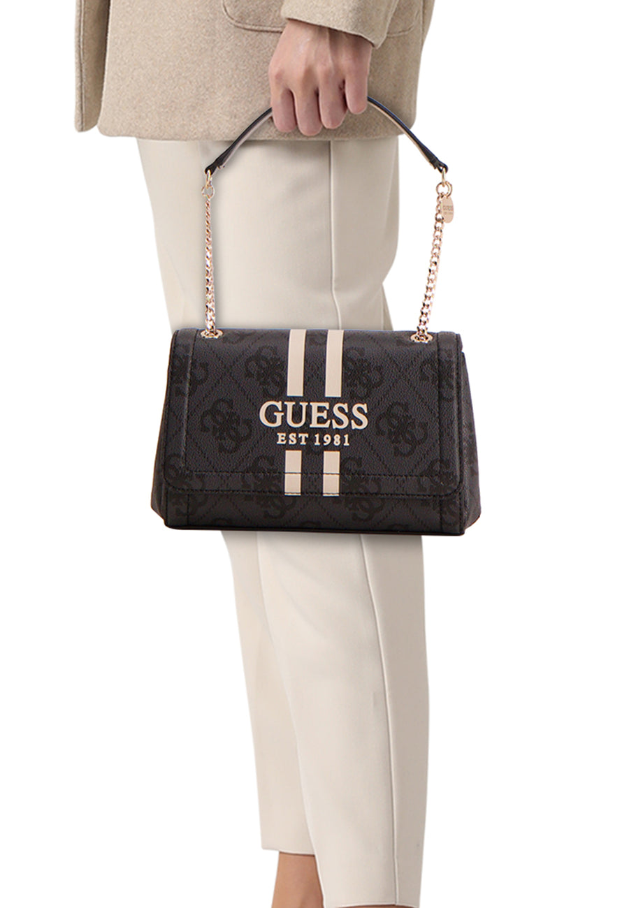 Zwarte Guess schoudertas met printpatroon, strepen en gouden kettingriem, gedragen met een beige jas en een witte broek.
