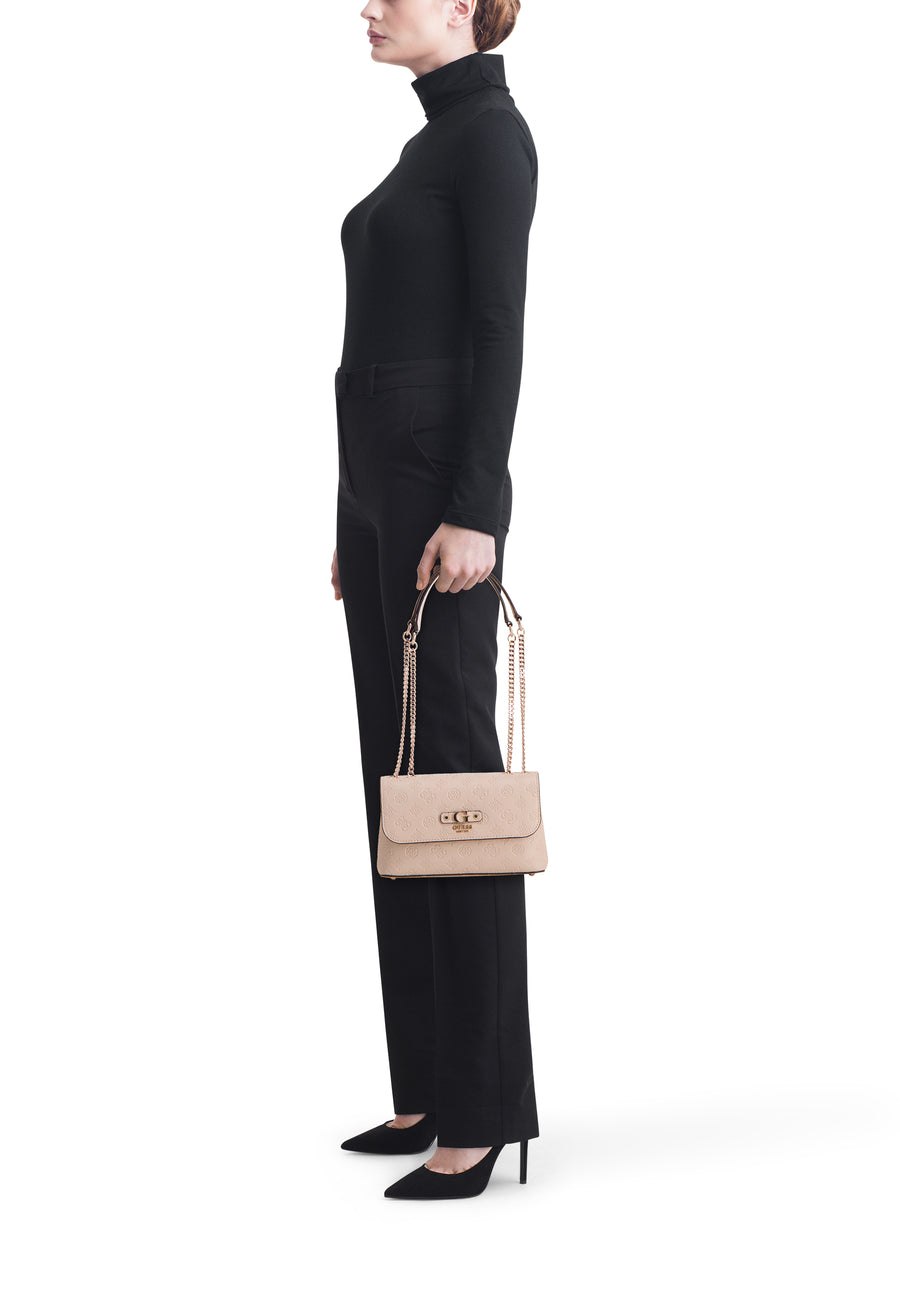 Beige Guess schoudertas, in de hand gedragen met een decoratieve ketting, gedragen met een zwarte trui en broek.