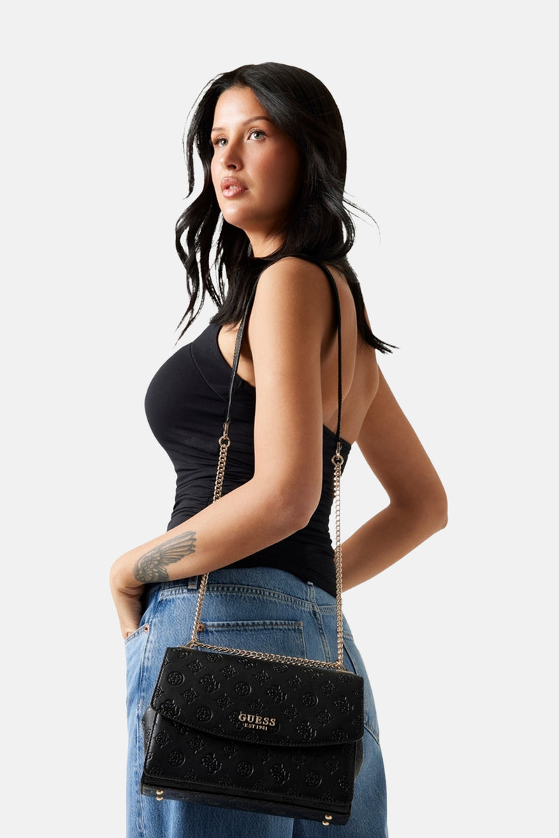 Zwarte textuur schoudertas van Guess, met gouden ketting en gedragen door een model in een zwarte tanktop en jeans.