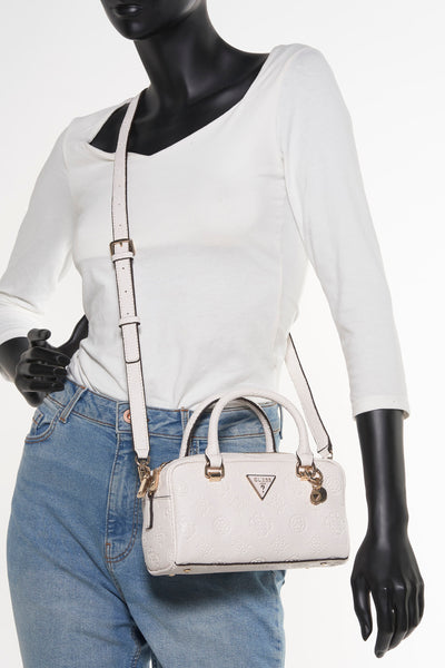 Sac à main blanc de Guess, avec motif logo en relief, porté avec un jean bleu et un haut blanc à manches longues.
