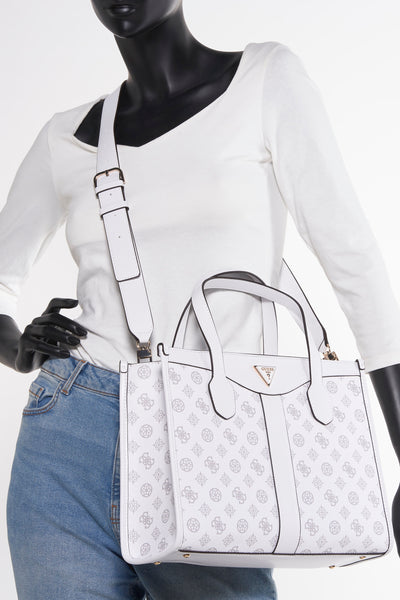 Witte Guess handtas met print, gedragen door een model in spijkerbroek en wit hemd.