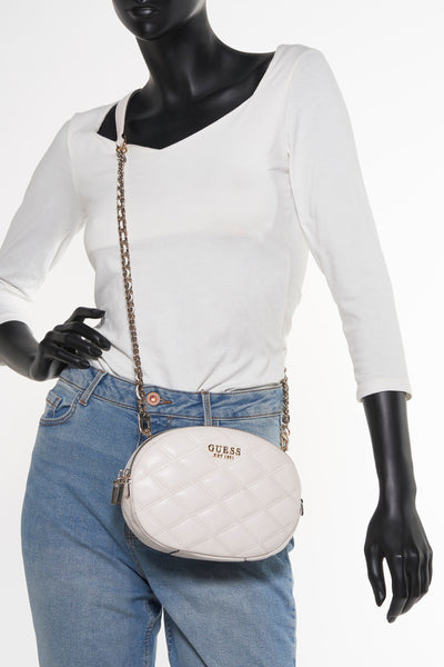 Witte Guess schoudertas, gedragen met een decoratieve ketting en een blauwe jeans.