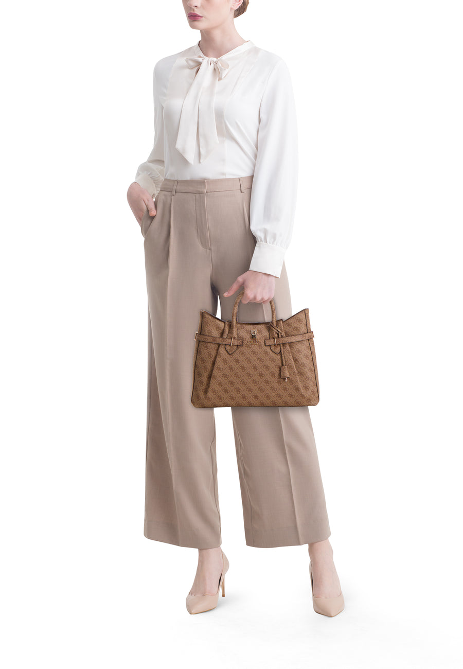 Bruine handtas met logopatroon, van Guess, gedragen met een beige broek en een witte geknoopte blouse.