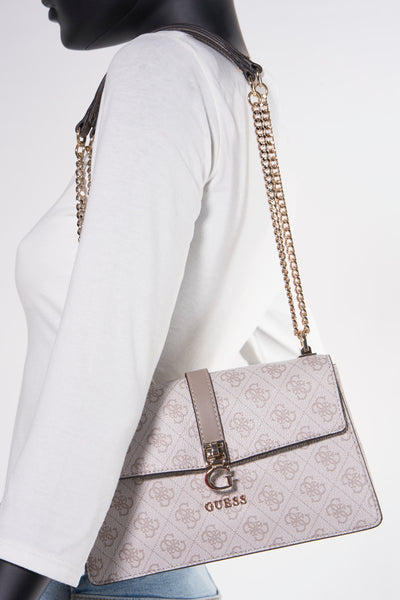 Sac à bandoulière beige de Guess avec motif imprimé, bandoulière en chaîne dorée et mannequin portant un haut blanc.
