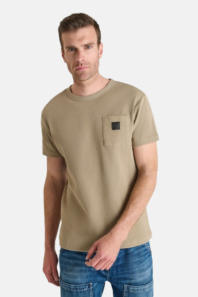 Beige T-shirt met korte mouwen van Le Temps des Cerises met vierkante borstzak, gedragen met een spijkerbroek.