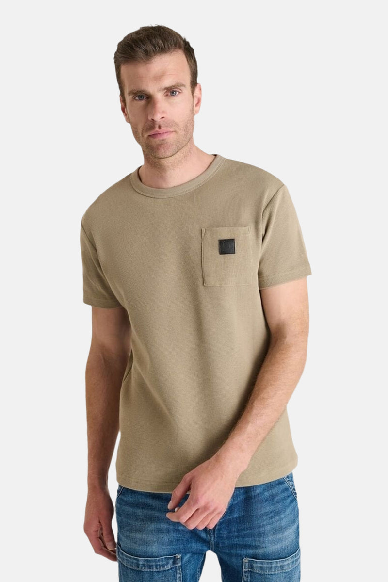 Beige T-shirt met korte mouwen van Le Temps des Cerises met vierkante borstzak, gedragen met een spijkerbroek.