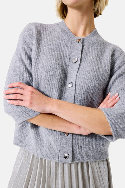 Grijze cardigan van GARCIA, geribde breinafwerking met zilveren knopen, gedragen met een zilveren plooirok.