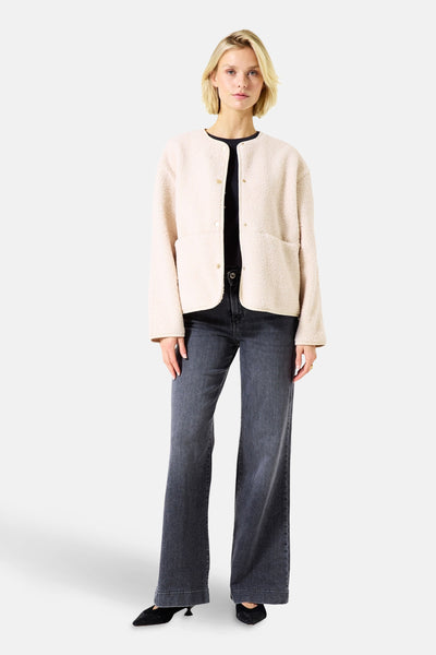 Ecru teddyjas van GARCIA, gedragen met een zwart T-shirt, een donkergrijze high-waist jeans en zwarte pumps.