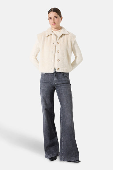 Beige mouwloos vest van GARCIA, met kraag en knopen, gedragen over een coltrui en een grijze flared jeans.