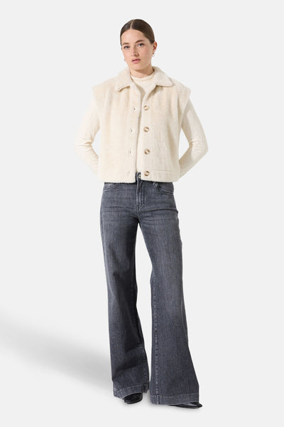 Beige mouwloos vest van GARCIA, met kraag en knopen, gedragen over een coltrui en een grijze flared jeans.