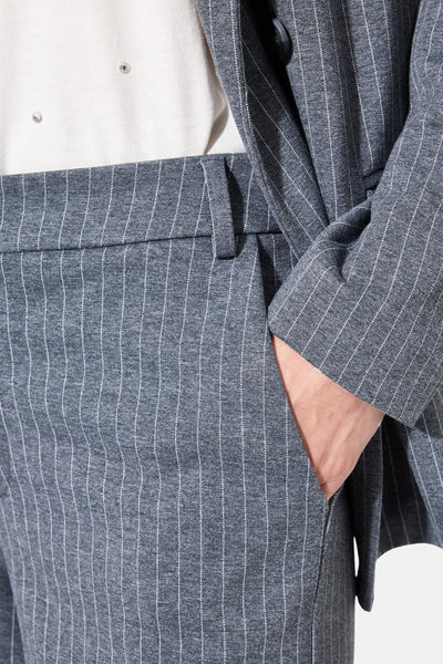 Pantalon de costume gris à rayures fines de GARCIA, avec une main dans la poche et un blazer assorti.
