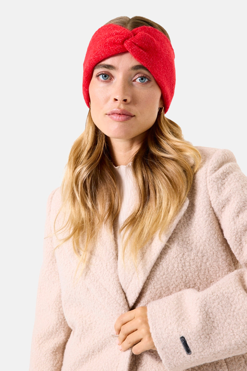 Cache-oreilles rouge de GARCIA, avec un design torsadé, porté avec un manteau texturé couleur crème.