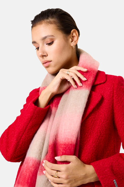 Écharpe à rayures rouge, rose et beige de GARCIA, portée avec un manteau rouge texturé et des bijoux dorés.