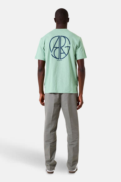 Groen T-shirt met korte mouwen van GARCIA, met logo op de rug gedrukt, gedragen met een grijze broek en witte sportschoenen.