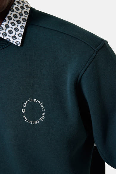 Groene trui van GARCIA, met een kraag met patroon en een geborduurd cirkelvormig logo op de borst.