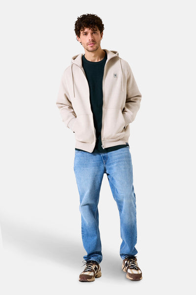 Beige gilet van GARCIA, gedragen met een donkergroen T-shirt, lichtblauwe jeans en bruine sportschoenen.