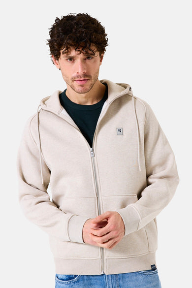 Beige GARCIA gilet, met rits en capuchon met koorden, gedragen over een zwart T-shirt en een blauwe spijkerbroek.