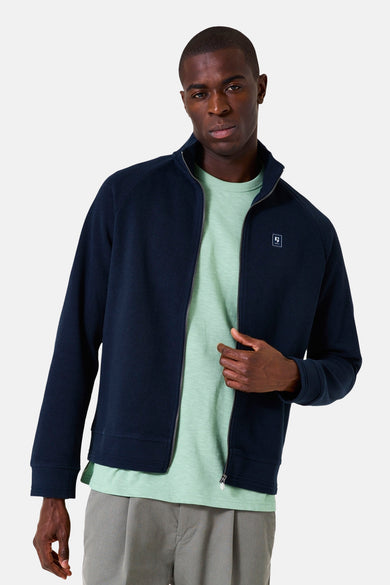 Gilet bleu marine de GARCIA avec une fermeture éclair argentée, porté sur un t-shirt vert clair et un pantalon gris.
