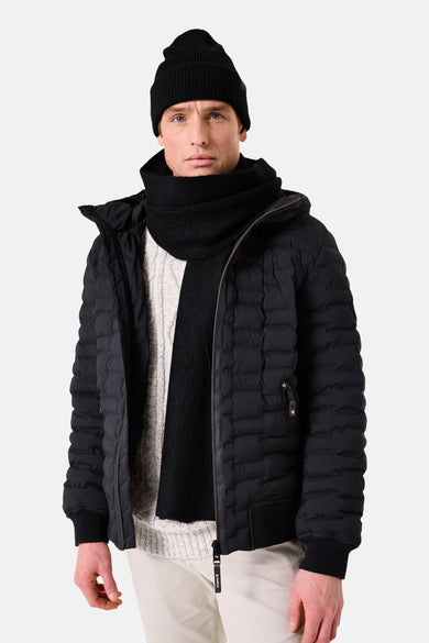 Écharpe noire par GARCIA, portée avec un bonnet noir et une veste matelassée.