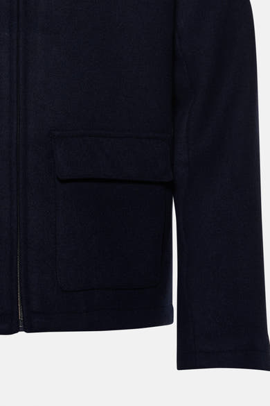 Détail d’une veste courte bleu marine INDIGOLD avec fermeture zippée et poches à rabat.