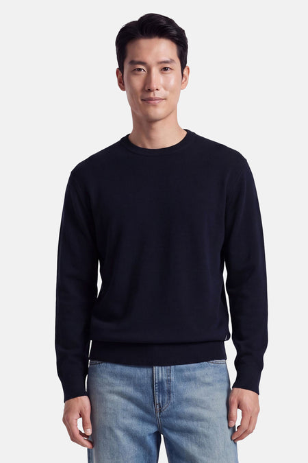 Pull col rond bleu marine de INDIGOLD, porté par un homme en jeans délavés, vue de face, coupe ajustée et finition côtelée aux manches et ourlet.
