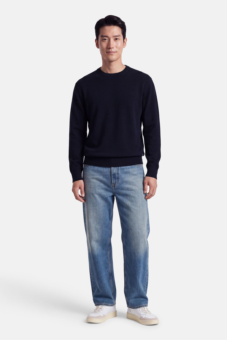 Pull col rond bleu marine par INDIGOLD, coupe ajustée, porté avec jeans délavés et baskets blanches, vue de face.