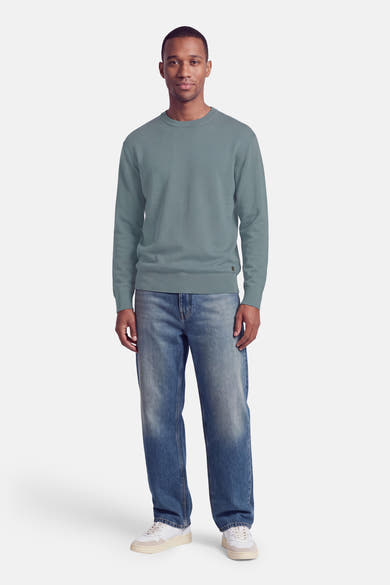 Pull col rond bleu marine par INDIGOLD, coupe ajustée, manches longues, bord-côte aux poignets et ourlet, porté avec jeans délavés et baskets blanches, vue de face.