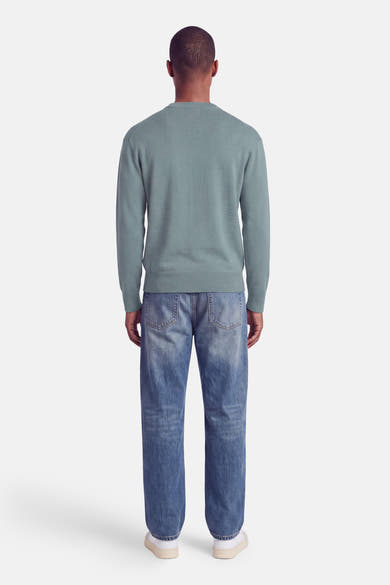 Pull col rond bleu clair de INDIGOLD, vue dos, avec finition côtelée aux manches et ourlet, porté avec jeans délavés et baskets blanches.