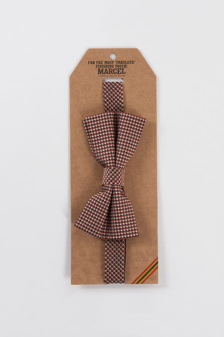 Paarse vlinderdas geweven door Le Fabuleux Marcel de Bruxelles, bordeauxrood en beige geruit patroon, op zijn kartonnen verpakking.