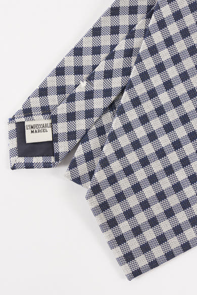 Cravate bleue à carreaux par Le Fabuleux Marcel de Bruxelles, avec motif vichy et étiquette de marque visible.