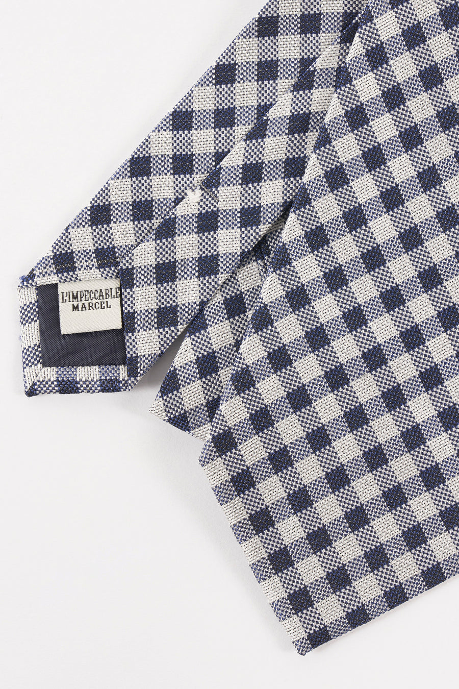 Cravate bleue à carreaux par Le Fabuleux Marcel de Bruxelles, avec motif vichy et étiquette de marque visible.