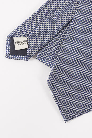 Blauwe stropdas van Le Fabuleux Marcel uit Brussel, met geometrisch patroon, op een witte achtergrond.
