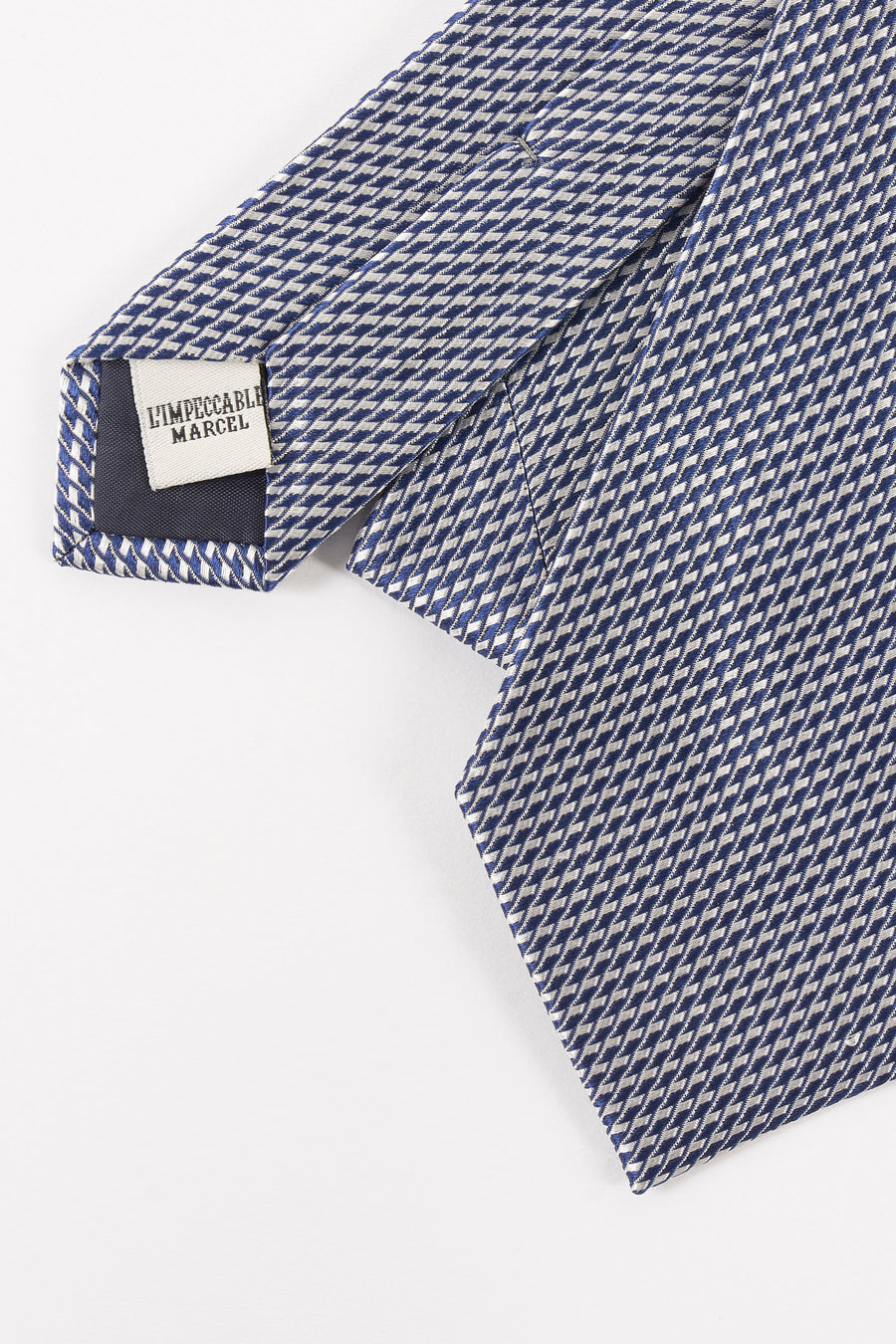 Blauwe stropdas van Le Fabuleux Marcel uit Brussel, met geometrisch patroon, op een witte achtergrond.
