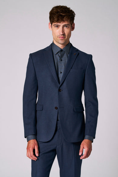Blazer bleu de Le Fabuleux Marcel de Bruxelles, avec une chemise à carreaux visible.