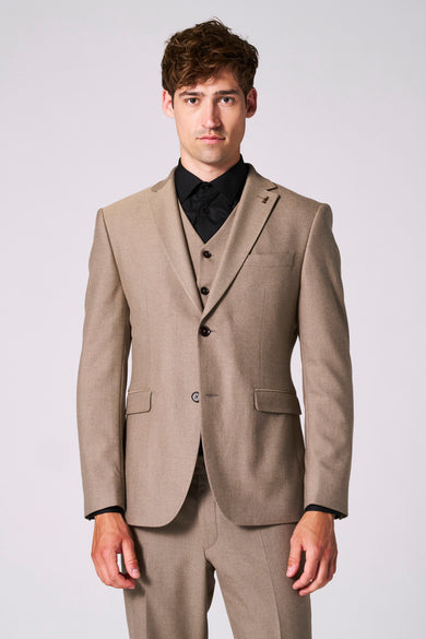 Beige blazer van Le Fabuleux Marcel uit Brussel, met inkeping revers en bruine knopen, gedragen over een zwart overhemd.