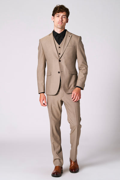 Beige blazer van Le Fabuleux Marcel uit Brussel, gedragen over een zwart overhemd en bruine schoenen.